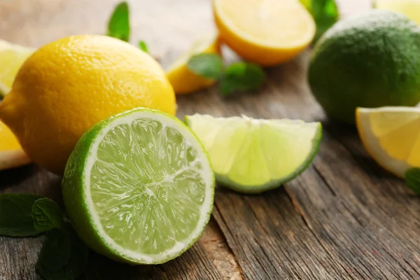 Skivade färska citroner och lime på träbord närbild — Stockfoto