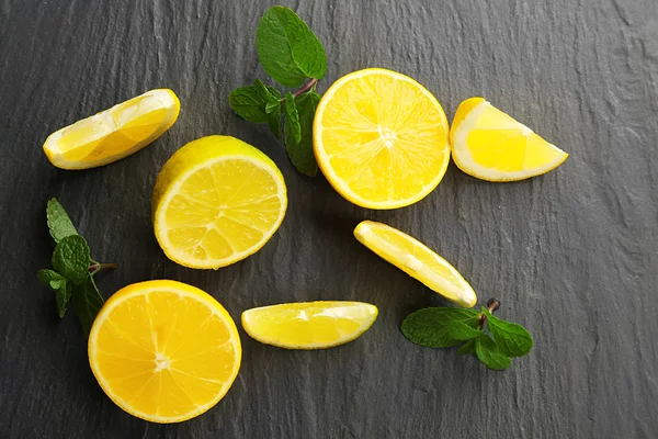 Tranches de citron frais et de citron vert sur fond texturé noir — Photo