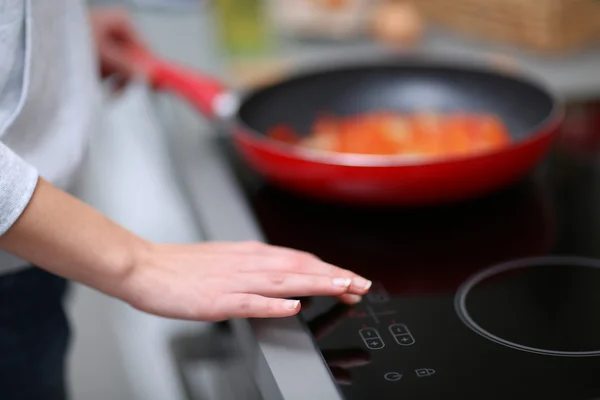 Main humaine avec poêle sur la cuisinière — Photo