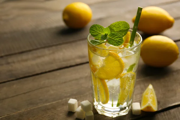 Limonada con limones, menta y terrones de azúcar sobre fondo de mesa de madera —  Fotos de Stock