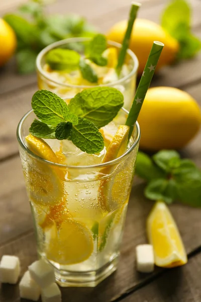 Two lemonades with lemons, mint and sugar cubes on wooden table background, closeup — Stock Photo, Image