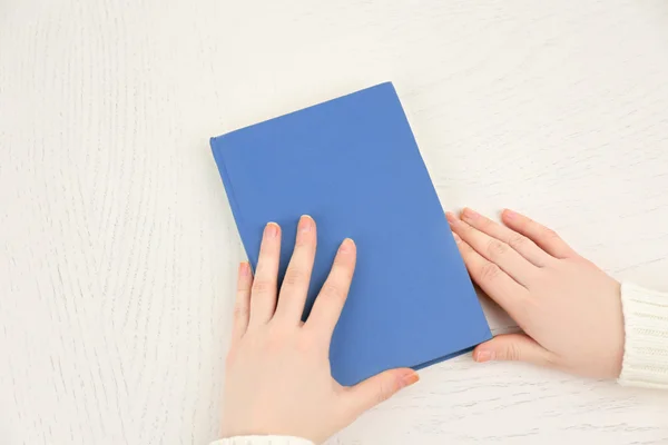 Weibliche Hände mit einem hellblauen Buch — Stockfoto