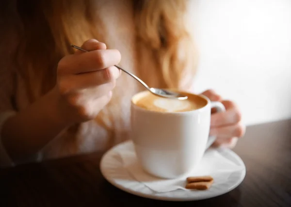 Donna con tazza di cappuccino sul tavolo nel caffè — Foto Stock