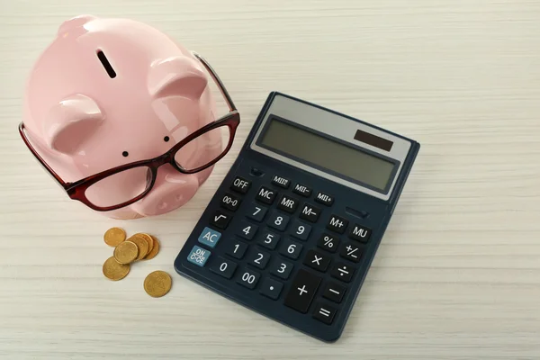 Banco porquinho com moedas, óculos e calculadora — Fotografia de Stock
