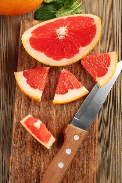 Skivad grapefrukt med mynta på träplatta, närbild — Stockfoto