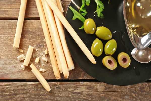 Bread sticks with arugula, oil and olives on plate — Stock Photo, Image