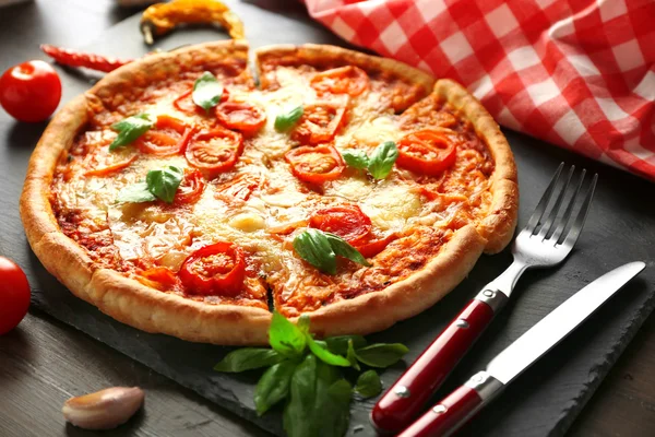 Margherita pizza with utensils and vegetable on slate plate — Stock Photo, Image