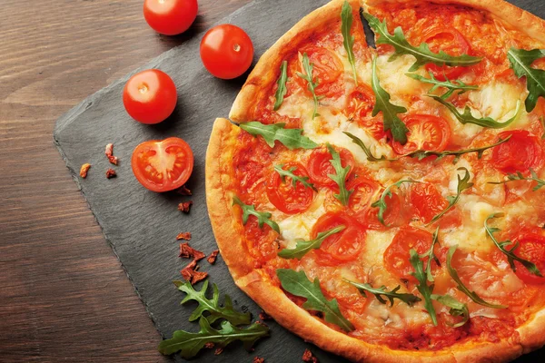 Pizza margherita con tomates y rúcula en plato de pizarra —  Fotos de Stock