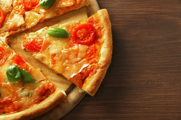 Margherita pizza ahşap arka plan üzerine dilimlenmiş — Stok fotoğraf