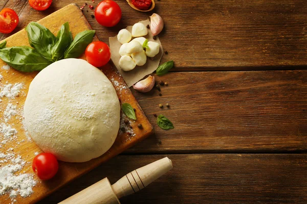 Pizza deeg met tomaten, groene basilicum en Mozzarella op houten achtergrond — Stockfoto