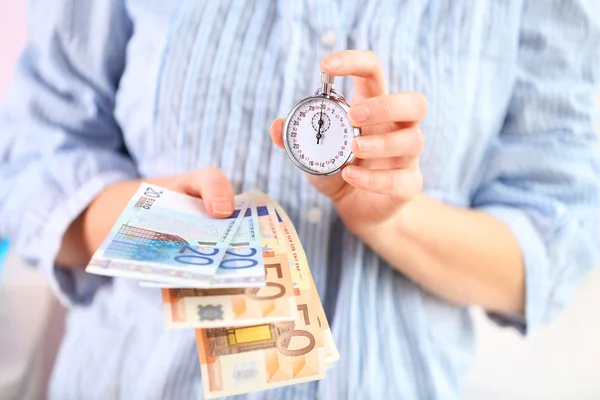 Женщина держит деньги и секундомер в руках — стоковое фото