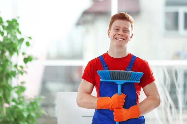 Joven conserje sosteniendo cepillo de piso — Foto de Stock