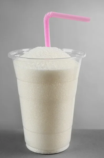 플라스틱 유리 회색 배경에 짚으로 설탕의 전체 — 스톡 사진