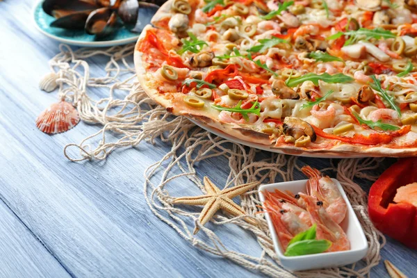 Pizza met zeevruchten, rode peper en groene olijven op blauwe houten tafel — Stockfoto