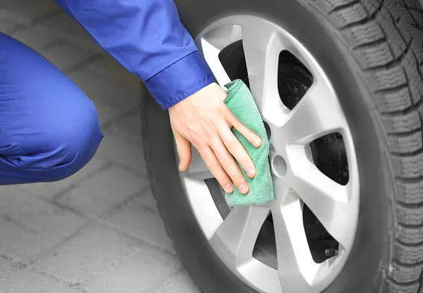 Jeune homme nettoyage roue de voiture — Photo