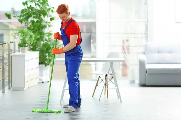 Conserje joven con piso de limpieza cepillo — Foto de Stock