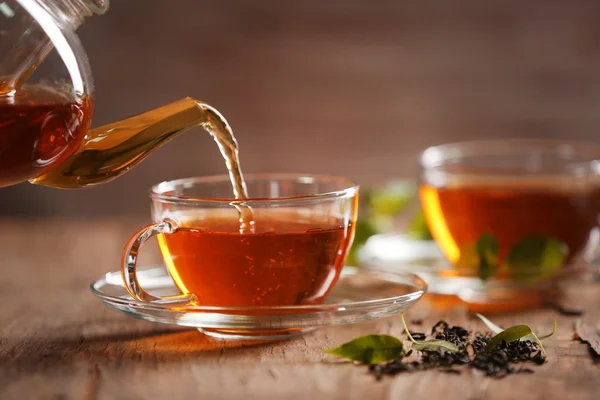 Teapot pouring tea in cup — Stock Photo, Image