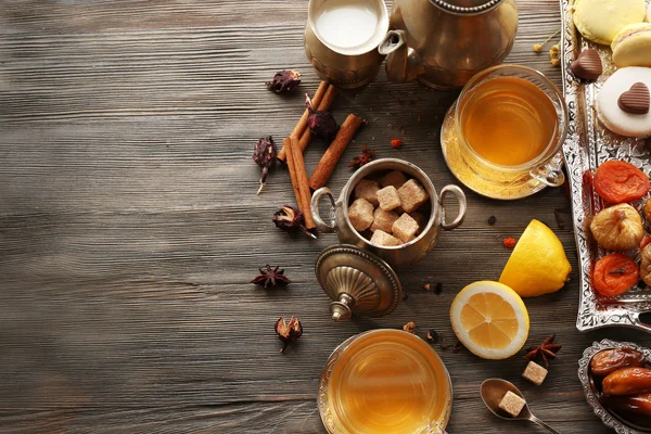 Tazza di tè preparato con limone, dolci orientali e spezie sul tavolo di legno — Foto Stock