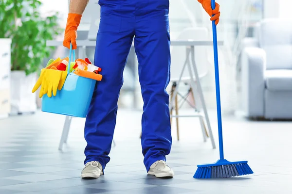 Joven conserje sosteniendo productos de limpieza —  Fotos de Stock