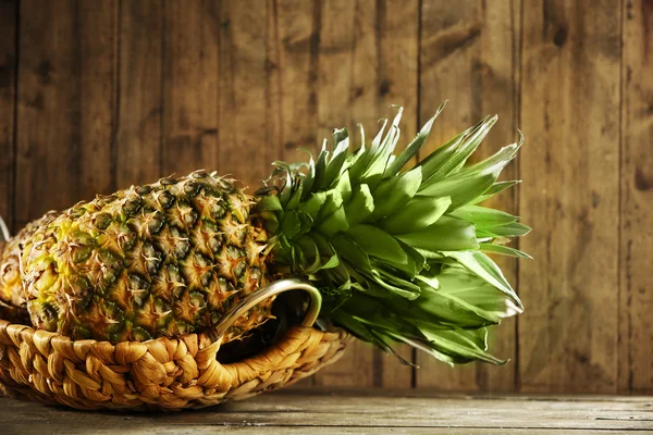 Hasır tepsi ahşap arka plan üzerinde olgunlaşmış sulu ananas — Stok fotoğraf