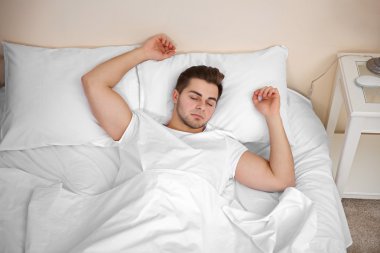 Genç adam yatakta uyuyor.