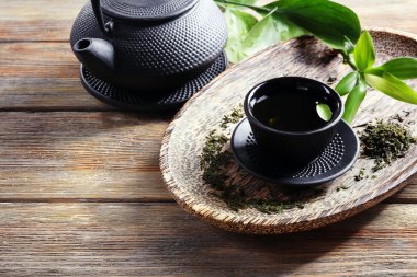 Yeşil çay ile ahşap masa üzerinde siyah mutfak eşyaları