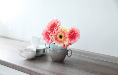 Ahşap masa üzerinde dishware ile pembe gerbera buketi