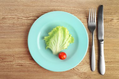 Salata yaprağı ve ahşap masa üzerinde domates ile servis tabağı