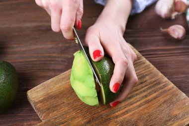 Bir avokado ikiye keserek eller