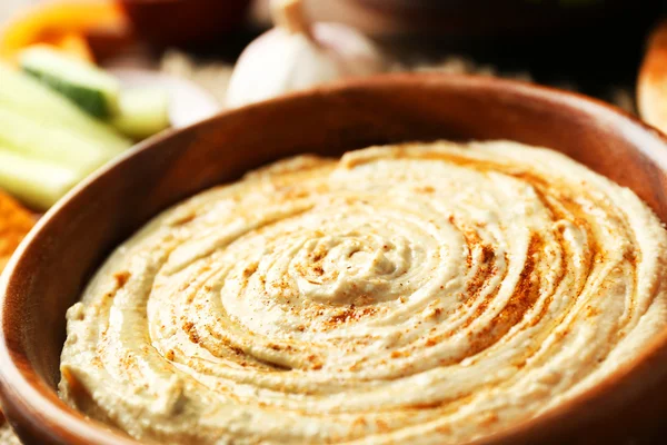 Hölzerne Schüssel mit schmackhaftem Humus — Stockfoto