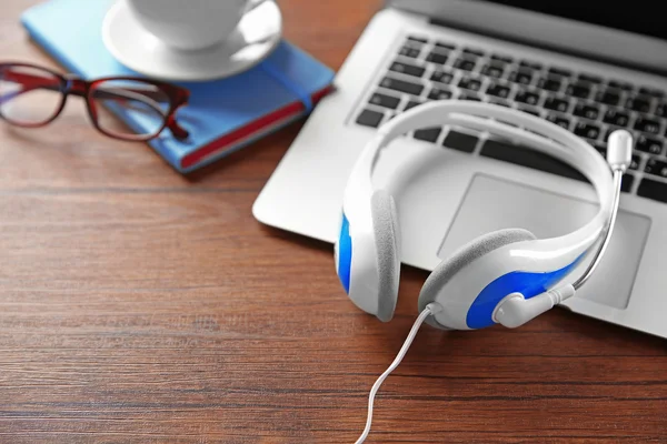 Auriculares y portátil en la mesa — Foto de Stock