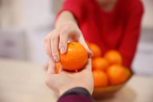 Woman giving tangerine — Stock Photo, Image