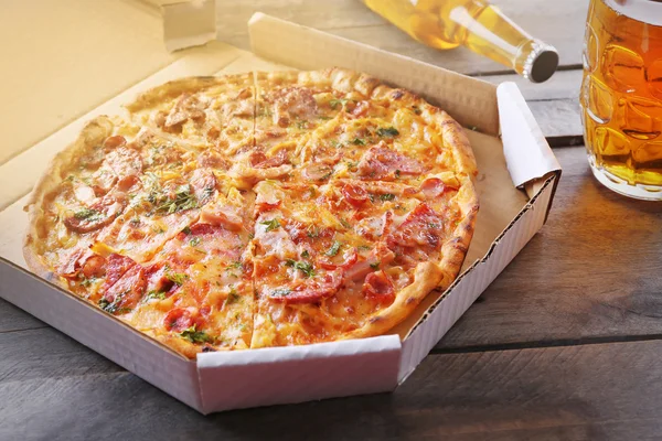 Lekkere pizza in karton en glas bier — Stockfoto