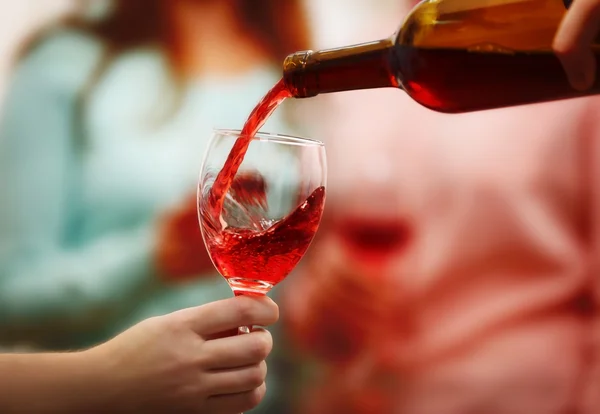 Pouring red wine into glass at hen-party, close up