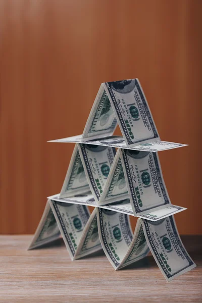 Peníze pyramida na dřevěný stůl — Stock fotografie