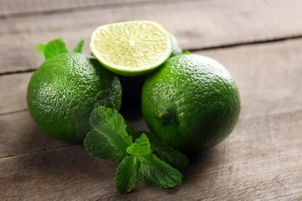 Limes with mint on wooden table — Stock Photo, Image