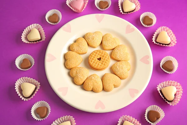 Biscuits savoureux et bonbons pour la Saint Valentin sur fond violet — Photo