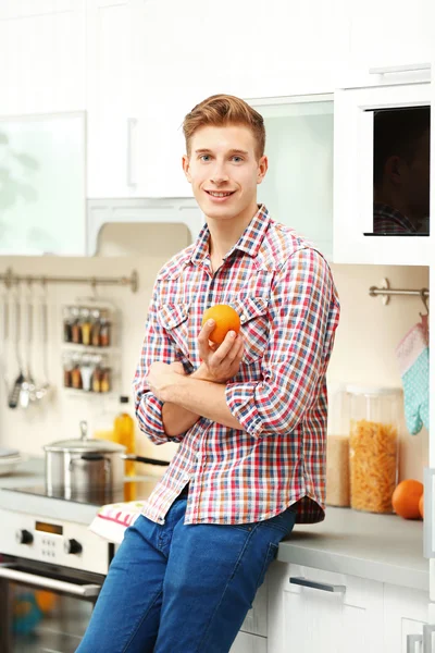 Man with orange in kitchen — Stock Photo, Image