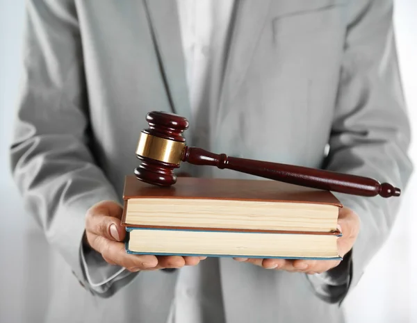 Man holding books with wooden gavel — Stock Photo, Image