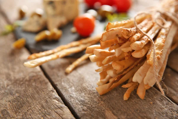 Pão varas grissini com queijo e tomates em uma mesa de madeira, close-up — Fotografia de Stock