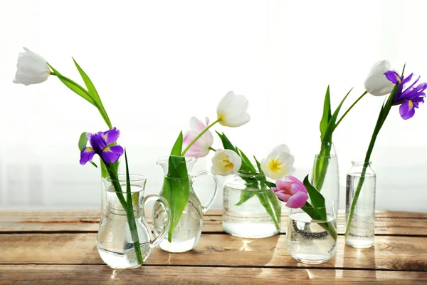 Tulips and purple iris in glass vases — Stock Photo, Image