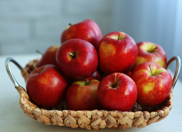 Ripe red apples in wicker basket on a kitchen table — Stock Photo, Image