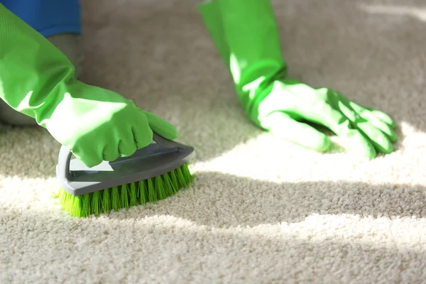 Mujer limpia alfombra en la habitación — Foto de Stock