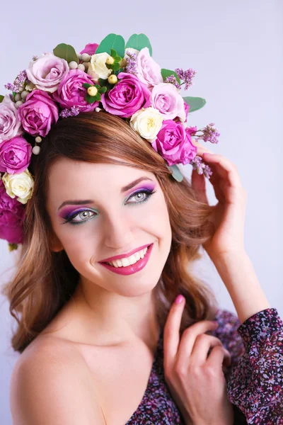 Hermosa mujer joven con diadema floral sobre un fondo gris —  Fotos de Stock