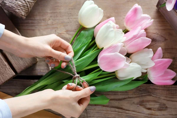 Mains féminines liant les tulipes — Photo