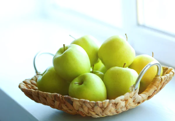 Maturare mele verdi in un cesto di vimini sul davanzale della finestra — Foto Stock