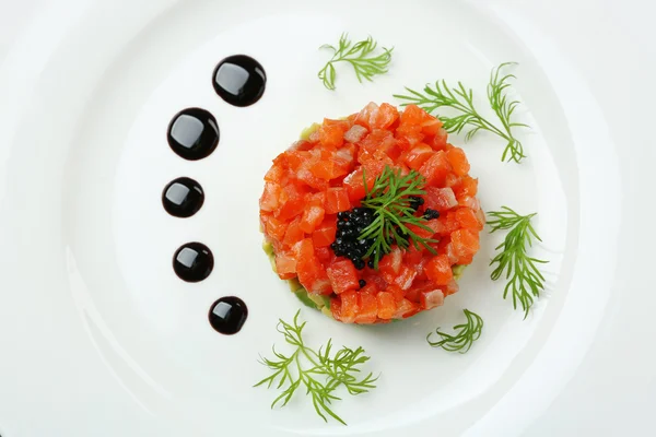 Delicious salmon tartare with black caviar on white plate — Stock Photo, Image