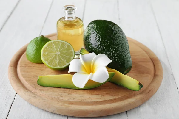 Avocado, plumeria, lime and oil on cutting board — Stock Photo, Image