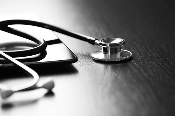 Stethoscope and tablet on wooden background — Stock Photo, Image