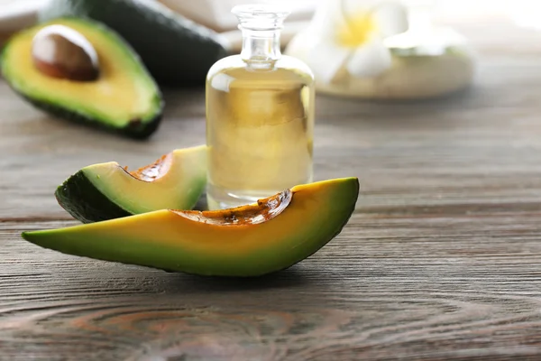 Aguacates frescos con un aceite sobre una mesa de madera, de cerca —  Fotos de Stock